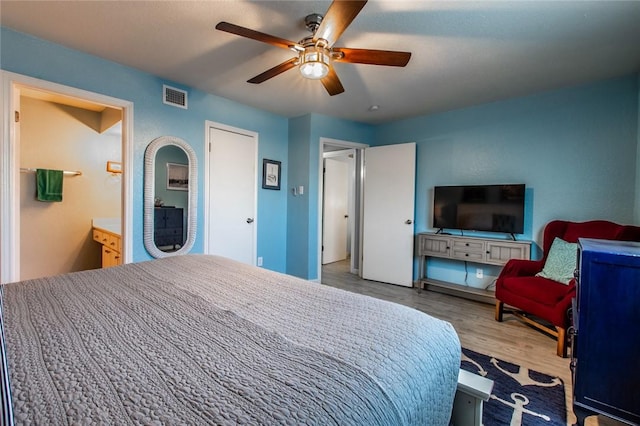 bedroom with ensuite bath, ceiling fan, and hardwood / wood-style flooring