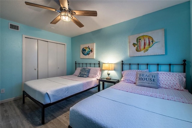 bedroom featuring dark hardwood / wood-style flooring, ceiling fan, and a closet