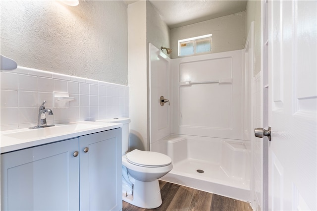 bathroom featuring tile walls, hardwood / wood-style flooring, toilet, and a shower