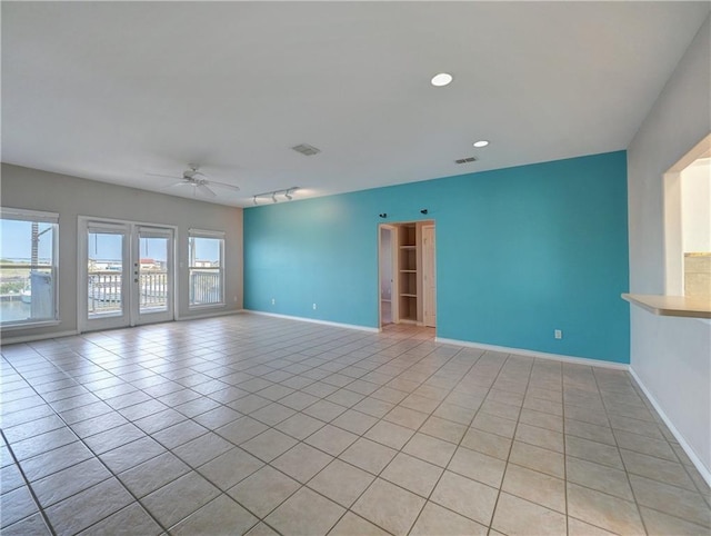 empty room featuring a ceiling fan, visible vents, baseboards, and light tile patterned floors