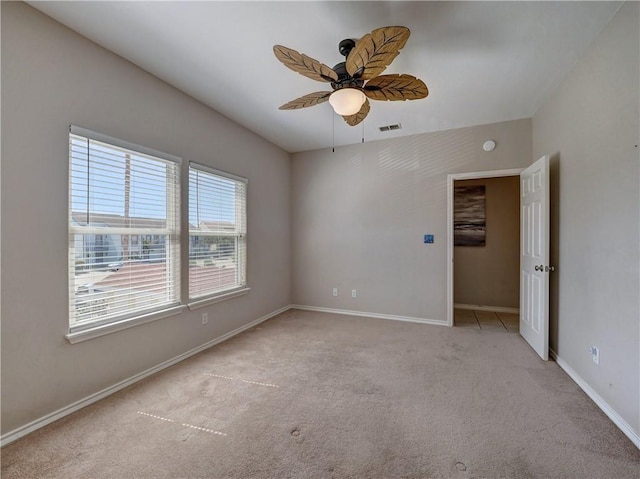 carpeted spare room featuring ceiling fan, visible vents, and baseboards