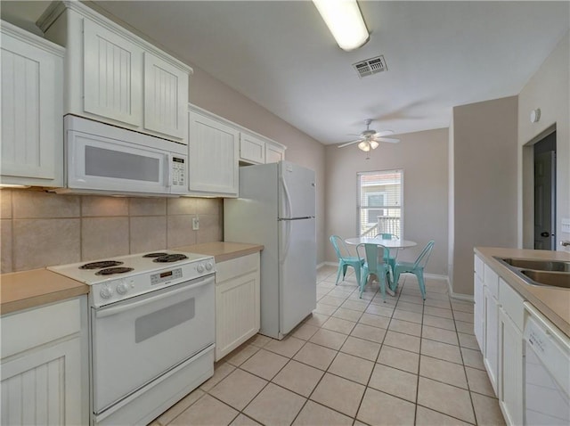 kitchen with light tile patterned floors, white appliances, a sink, visible vents, and tasteful backsplash