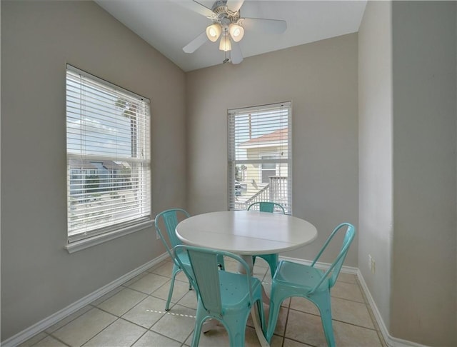 dining space featuring a ceiling fan, baseboards, and light tile patterned floors