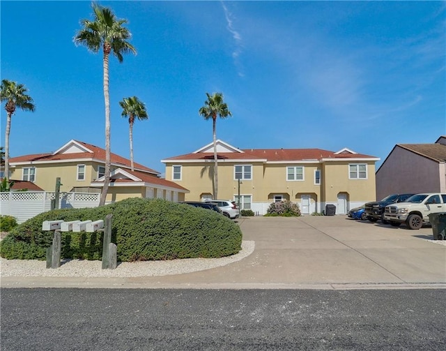 view of front of house with uncovered parking, fence, a residential view, and stucco siding