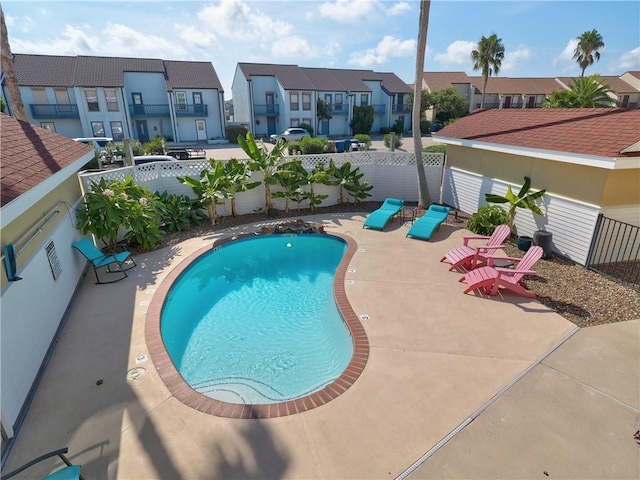 community pool featuring a residential view, a fenced backyard, and a patio