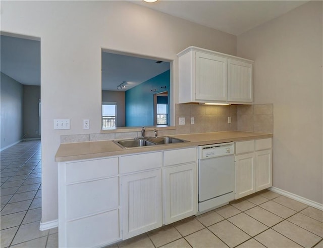 kitchen with light countertops, backsplash, white dishwasher, and a sink