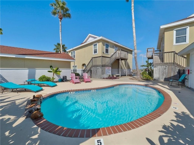 community pool with stairs, a patio, and fence