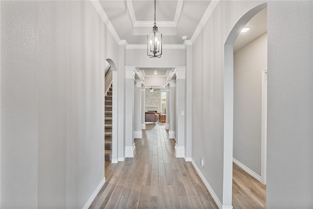 hallway featuring an inviting chandelier, arched walkways, baseboards, and wood finished floors