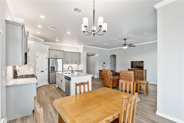 dining space featuring crown molding, arched walkways, baseboards, and ceiling fan with notable chandelier