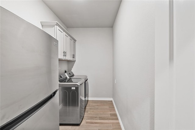 laundry room featuring light wood-style floors, baseboards, cabinet space, and washer and dryer
