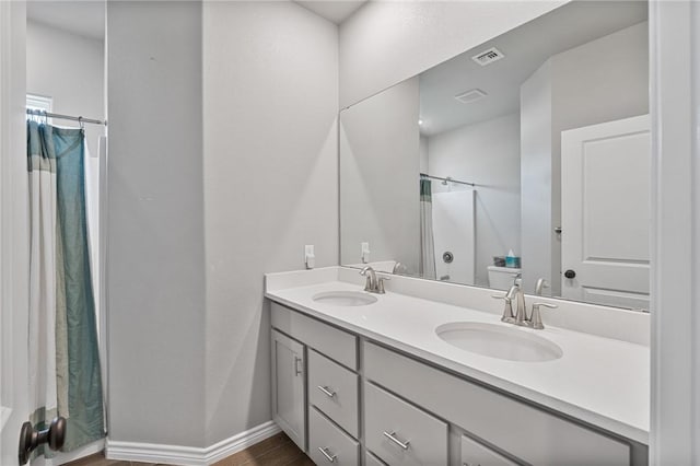 full bath with a sink, a shower with shower curtain, double vanity, and visible vents