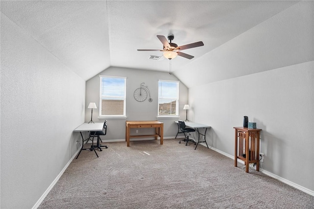 carpeted office space featuring visible vents, baseboards, ceiling fan, and vaulted ceiling