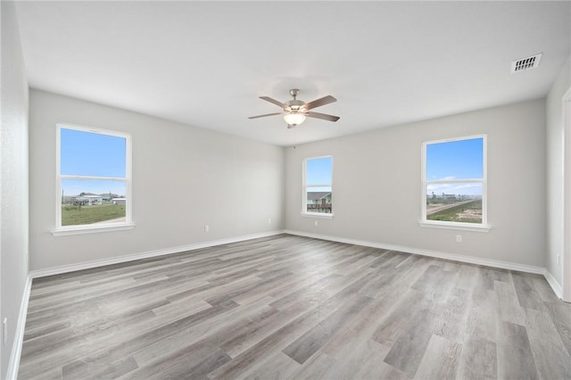 empty room featuring visible vents, baseboards, wood finished floors, and a ceiling fan