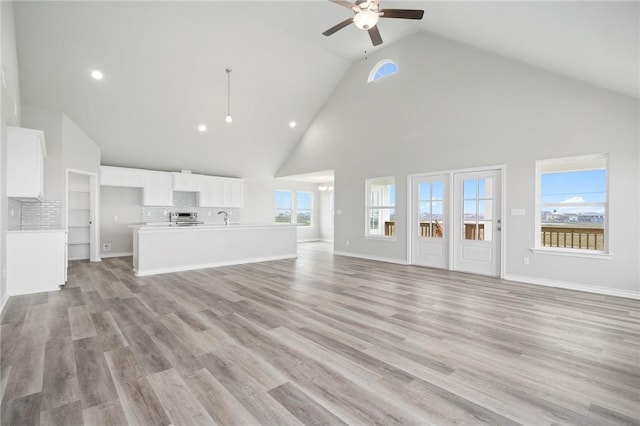 unfurnished living room with a healthy amount of sunlight, light wood-style floors, baseboards, and ceiling fan