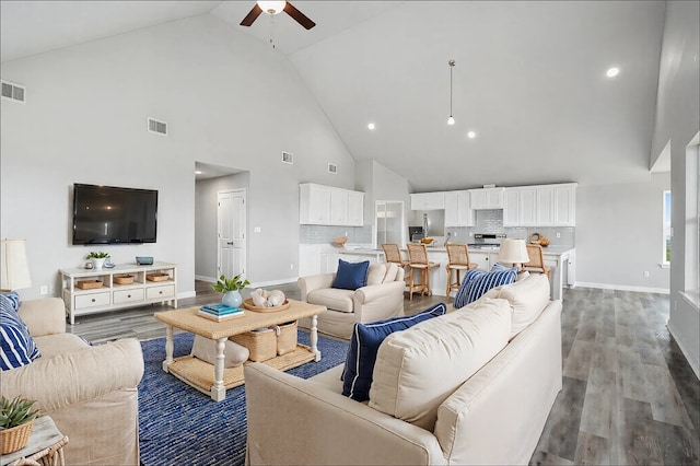 living area with baseboards, wood finished floors, visible vents, and ceiling fan