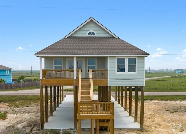 coastal home featuring stairs, a porch, a carport, and a shingled roof