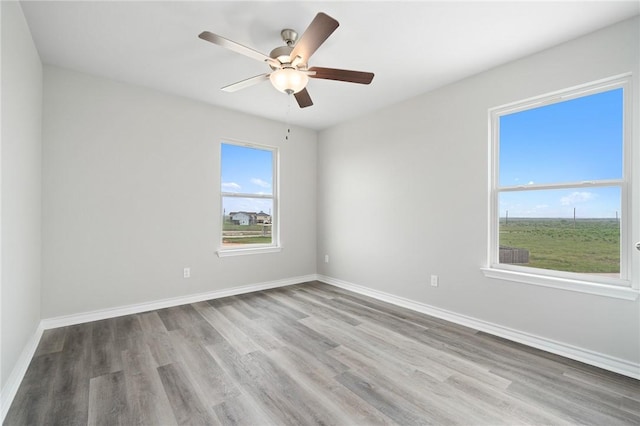 spare room featuring ceiling fan, baseboards, and wood finished floors