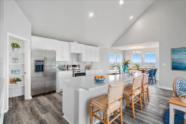 kitchen featuring white cabinets, appliances with stainless steel finishes, a kitchen breakfast bar, and a sink