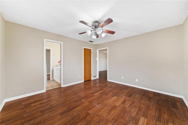 unfurnished bedroom with ensuite bath, ceiling fan, and dark wood-type flooring