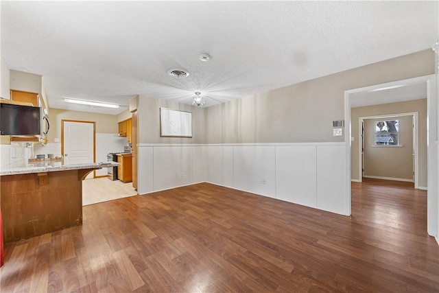 unfurnished living room with a textured ceiling and light hardwood / wood-style floors