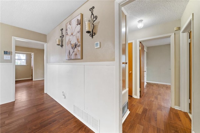 hallway with a textured ceiling and wood-type flooring