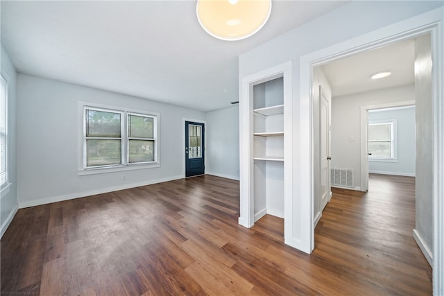 unfurnished living room featuring dark wood-type flooring and a wealth of natural light