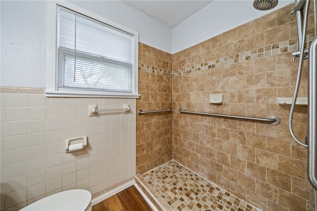 bathroom with tile walls, hardwood / wood-style flooring, and a tile shower