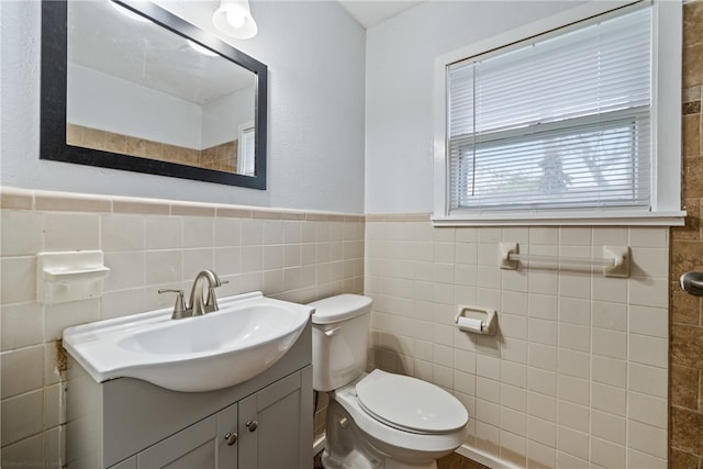 bathroom with vanity, toilet, and tile walls