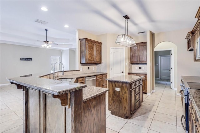 kitchen with a kitchen island, a breakfast bar, appliances with stainless steel finishes, hanging light fixtures, and kitchen peninsula