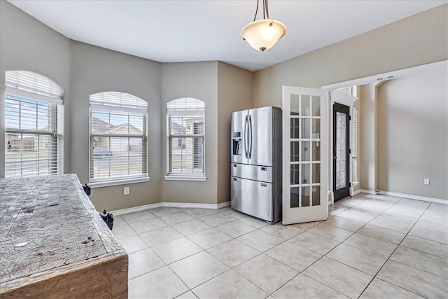 kitchen featuring light stone countertops, stainless steel fridge with ice dispenser, hanging light fixtures, and light tile patterned floors