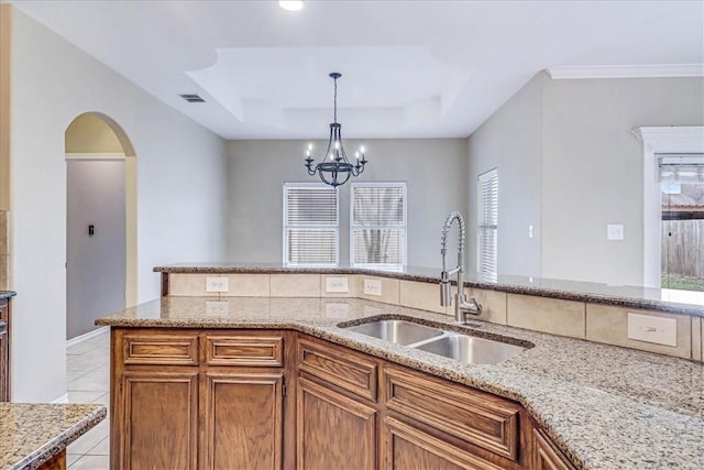 kitchen with decorative light fixtures, sink, light tile patterned floors, a notable chandelier, and a raised ceiling