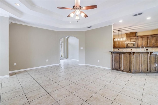 unfurnished living room with ceiling fan, a raised ceiling, sink, and light tile patterned floors