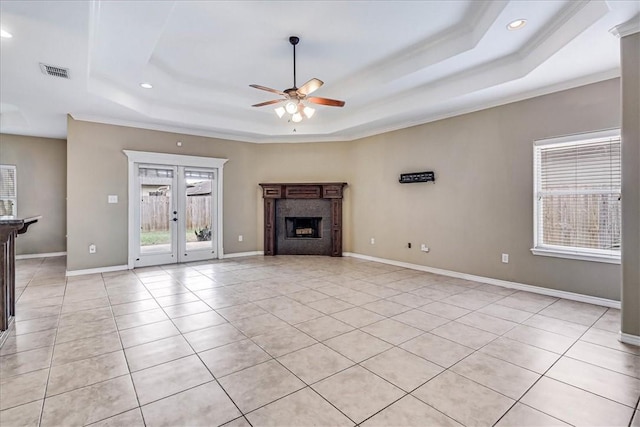 unfurnished living room with french doors, plenty of natural light, and a tray ceiling