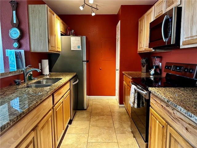 kitchen featuring rail lighting, sink, dark stone countertops, light tile patterned floors, and stainless steel appliances