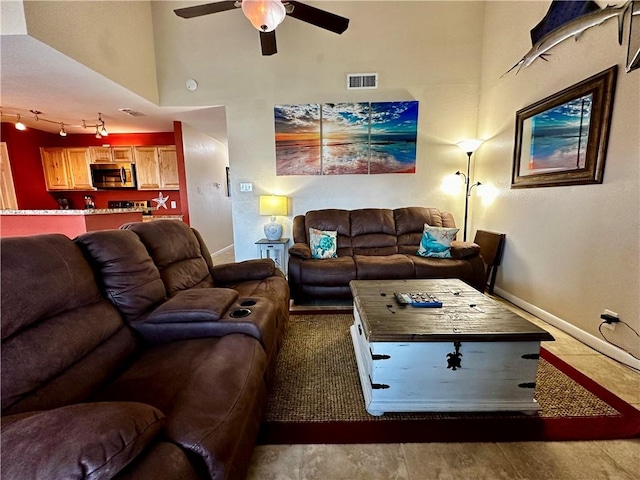 living room with ceiling fan and a towering ceiling