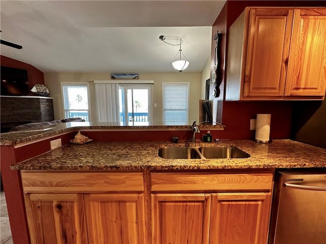 kitchen with stainless steel dishwasher, sink, dark stone countertops, and kitchen peninsula