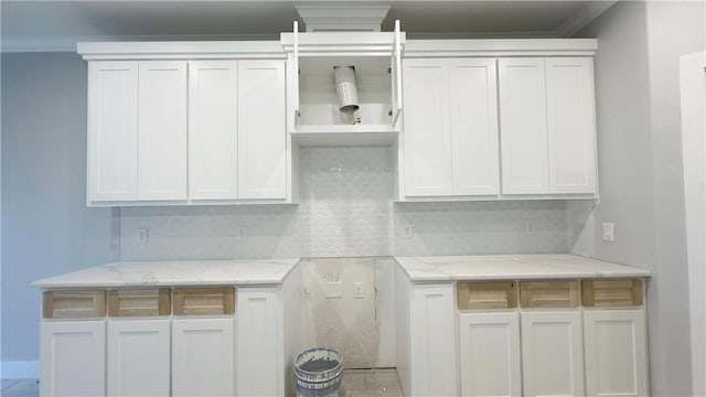 kitchen featuring white cabinets, light stone countertops, and tasteful backsplash