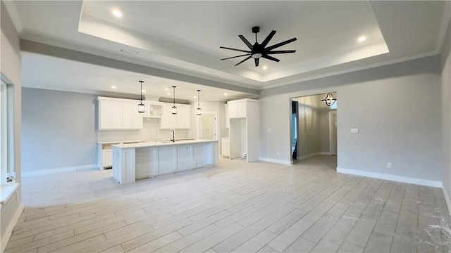 kitchen with a raised ceiling, open floor plan, and a ceiling fan