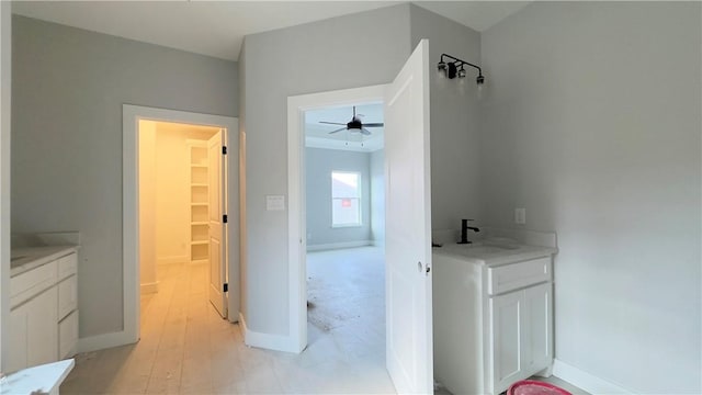 bathroom with vanity, wood finished floors, a ceiling fan, and baseboards