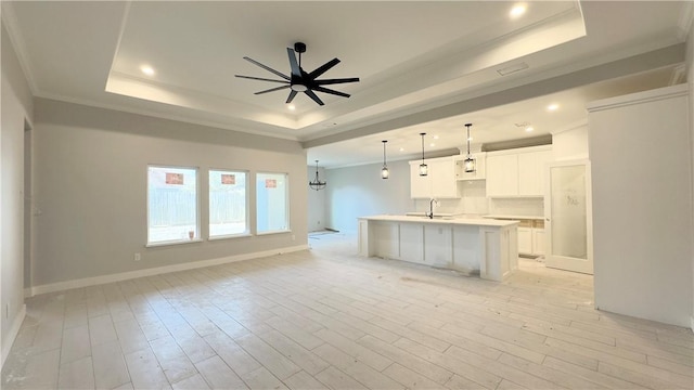 kitchen featuring a sink, a raised ceiling, open floor plan, and ceiling fan