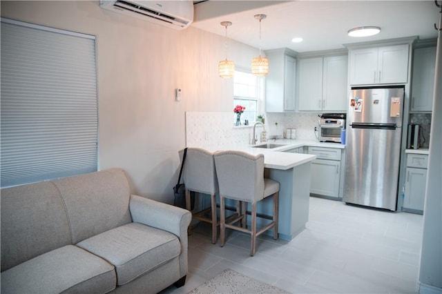 kitchen with a sink, freestanding refrigerator, a peninsula, open floor plan, and a breakfast bar area