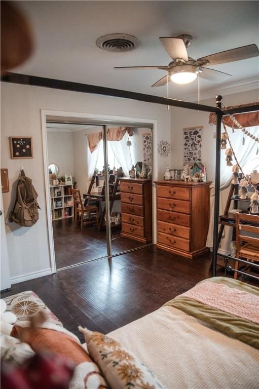bedroom with dark wood-style flooring, visible vents, crown molding, and ceiling fan