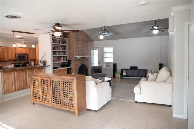 living area with a ceiling fan, visible vents, light tile patterned floors, and a brick fireplace
