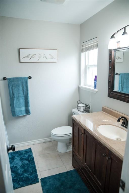 bathroom featuring baseboards, toilet, vanity, and tile patterned floors