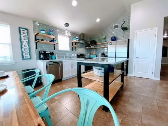 kitchen featuring tasteful backsplash, stainless steel appliances, white cabinetry, decorative light fixtures, and vaulted ceiling