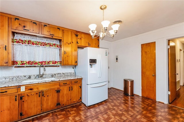 4114 Markins Dr, Corpus Christi, TX 78411 - kitchen with white fridge with ice dispenser, a chandelier, brown cabinets, ornamental molding, and hanging light fixtures