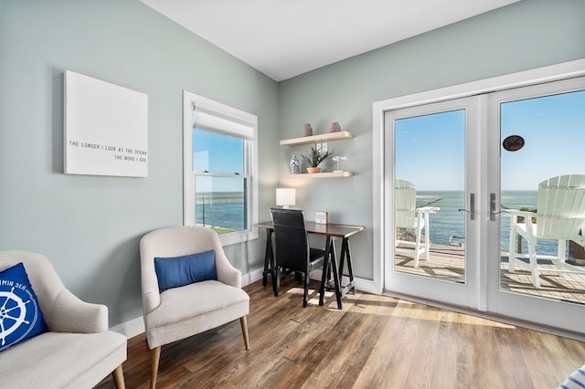 living area featuring french doors, a water view, and hardwood / wood-style flooring