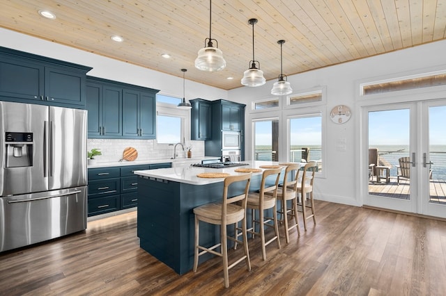 kitchen featuring hanging light fixtures, a kitchen island, appliances with stainless steel finishes, wooden ceiling, and a water view