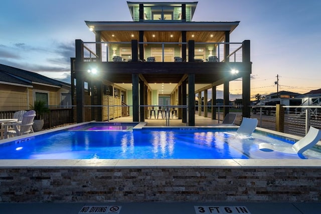 pool at dusk with a jacuzzi and a patio