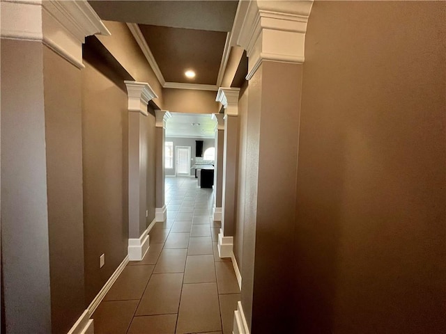 hallway featuring tile patterned flooring, baseboards, crown molding, and ornate columns